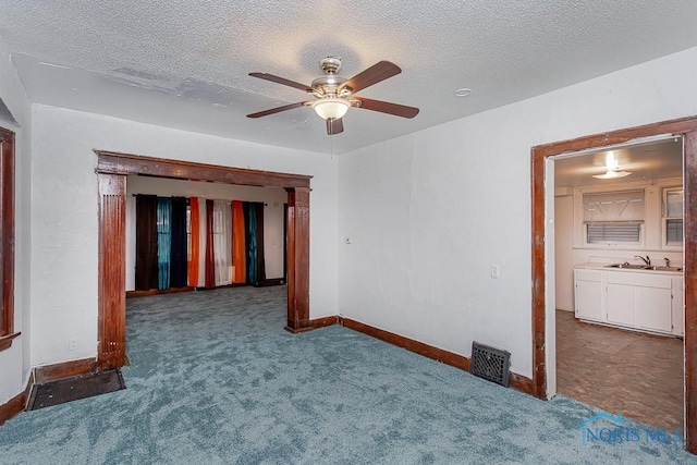 carpeted empty room with ceiling fan, sink, and a textured ceiling