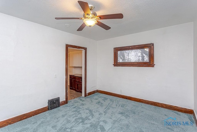 unfurnished bedroom with carpet, a textured ceiling, a walk in closet, and ceiling fan