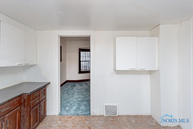 interior space with white cabinetry and light carpet