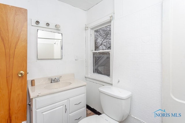 bathroom with vanity, tile walls, and toilet