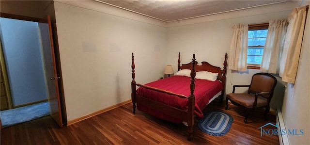 bedroom featuring baseboard heating and dark hardwood / wood-style floors