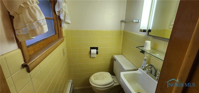 bathroom with a baseboard radiator, toilet, tile walls, and sink