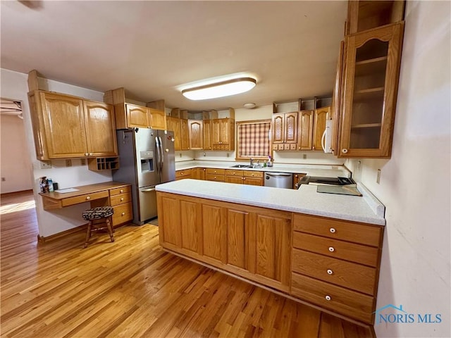 kitchen featuring kitchen peninsula, sink, stainless steel appliances, and light wood-type flooring