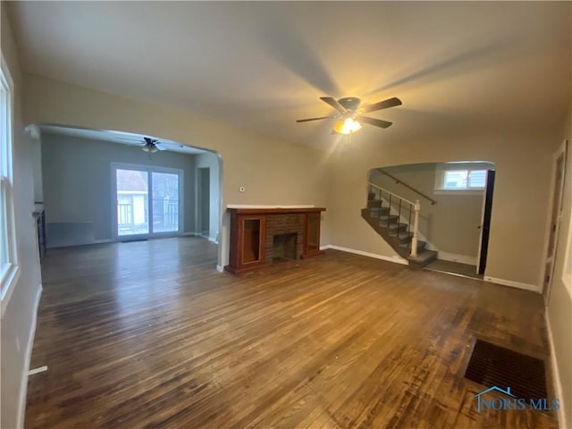 unfurnished living room with ceiling fan, dark hardwood / wood-style flooring, and a fireplace