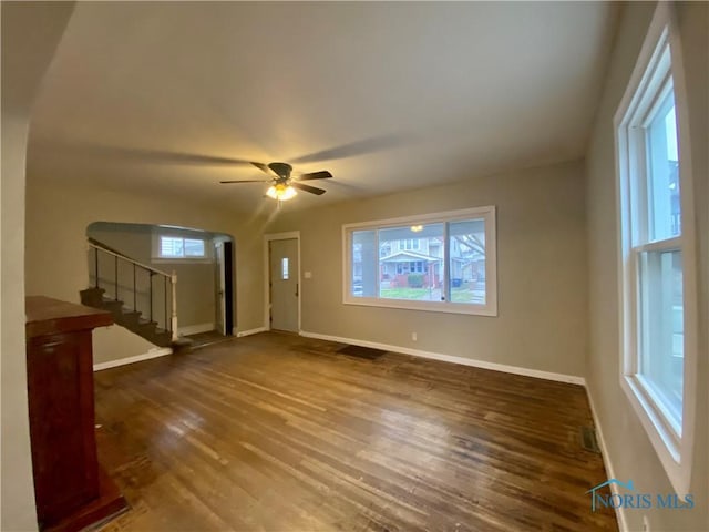 unfurnished living room featuring ceiling fan and dark wood-type flooring