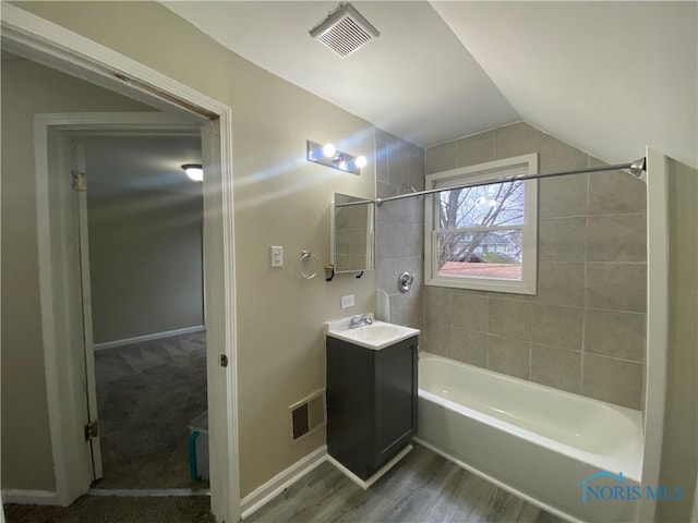 bathroom featuring hardwood / wood-style floors, vanity, vaulted ceiling, and tiled shower / bath