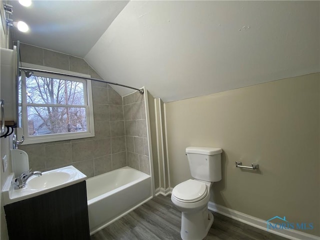 full bathroom featuring tiled shower / bath combo, vaulted ceiling, toilet, vanity, and hardwood / wood-style flooring