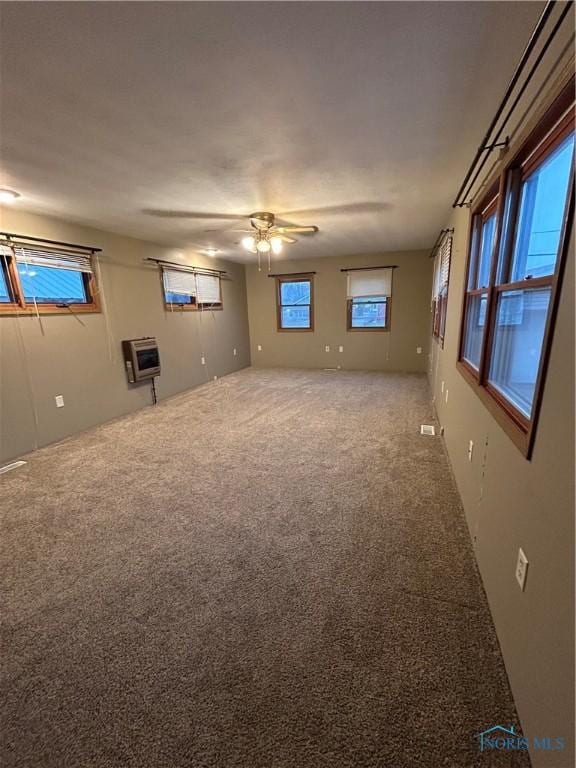 unfurnished room featuring carpet flooring, heating unit, and ceiling fan