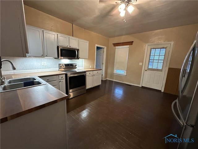 kitchen featuring wood counters, dark wood-type flooring, white cabinets, sink, and appliances with stainless steel finishes