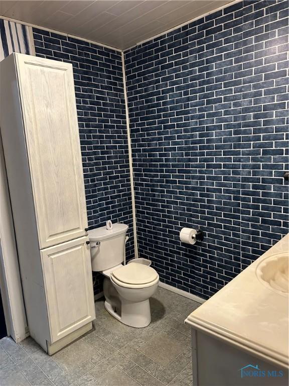 bathroom featuring vanity, toilet, and tile walls