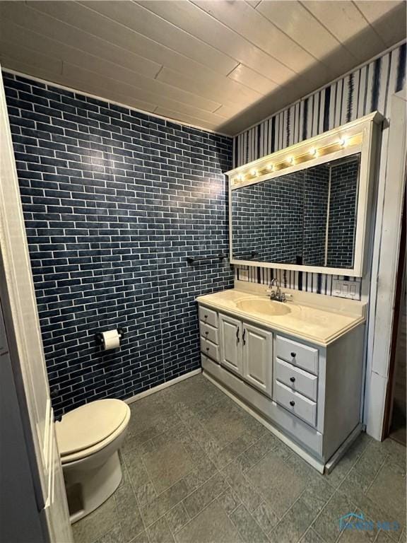 bathroom featuring vanity, toilet, and tile walls