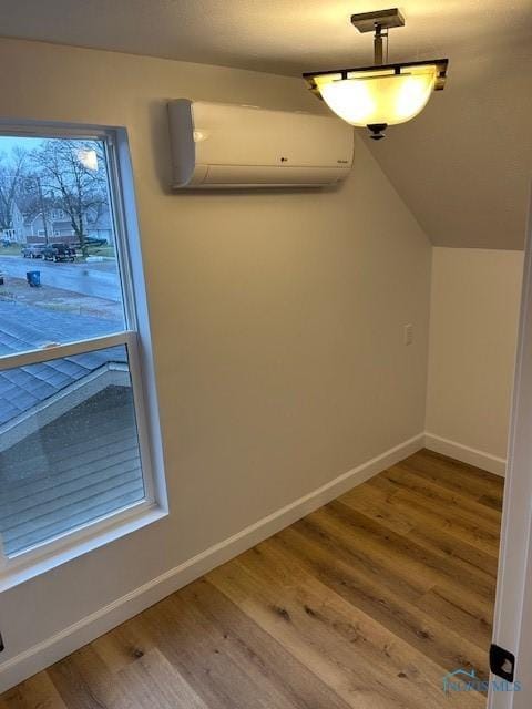 interior space with an AC wall unit, lofted ceiling, and hardwood / wood-style flooring