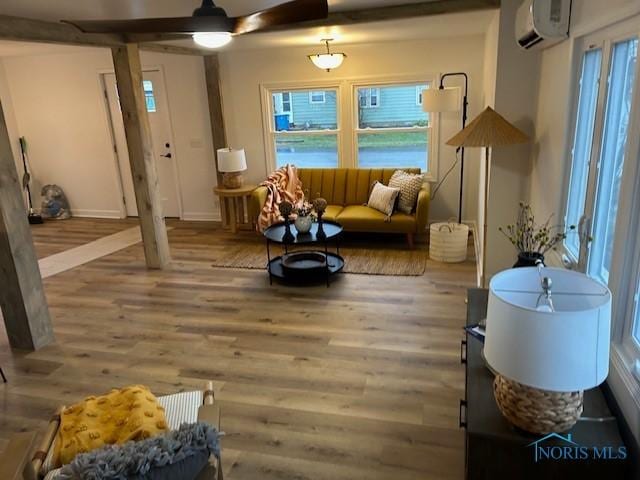 sitting room with hardwood / wood-style floors, a wall mounted AC, and ceiling fan