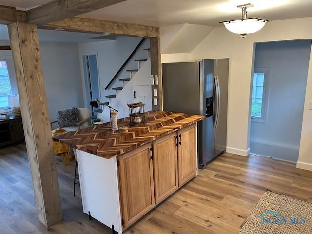 bar with a wealth of natural light, light hardwood / wood-style floors, stainless steel refrigerator with ice dispenser, and decorative light fixtures