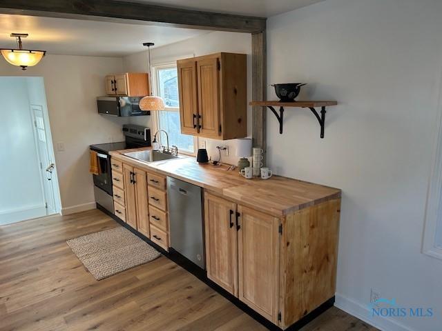 kitchen with hardwood / wood-style floors, pendant lighting, stainless steel appliances, and sink