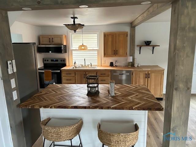 kitchen featuring pendant lighting, sink, light hardwood / wood-style flooring, butcher block countertops, and stainless steel appliances