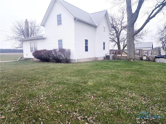 view of side of home with a yard, a deck, and central air condition unit