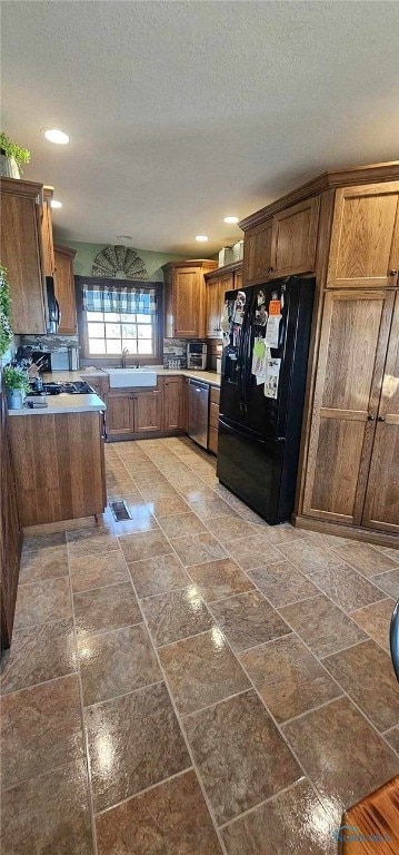 kitchen with sink, black fridge, stainless steel dishwasher, kitchen peninsula, and a textured ceiling