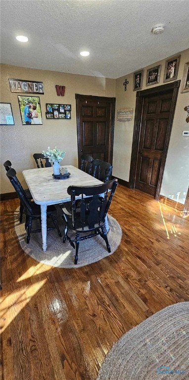 dining space with wood-type flooring and a textured ceiling