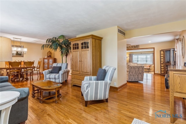 living room featuring a notable chandelier and light wood-type flooring