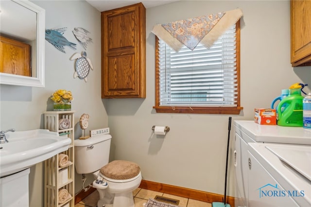 bathroom with toilet, washer and clothes dryer, and tile patterned flooring