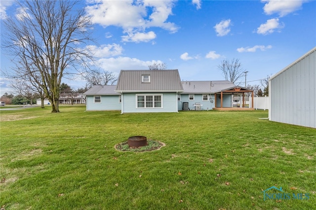 back of property with a yard and a fire pit