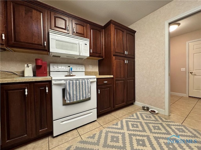 kitchen featuring dark brown cabinets, light tile patterned floors, and white appliances