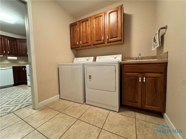 clothes washing area with cabinets, light tile patterned floors, sink, and washing machine and clothes dryer