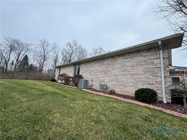 view of side of home with central AC unit and a lawn