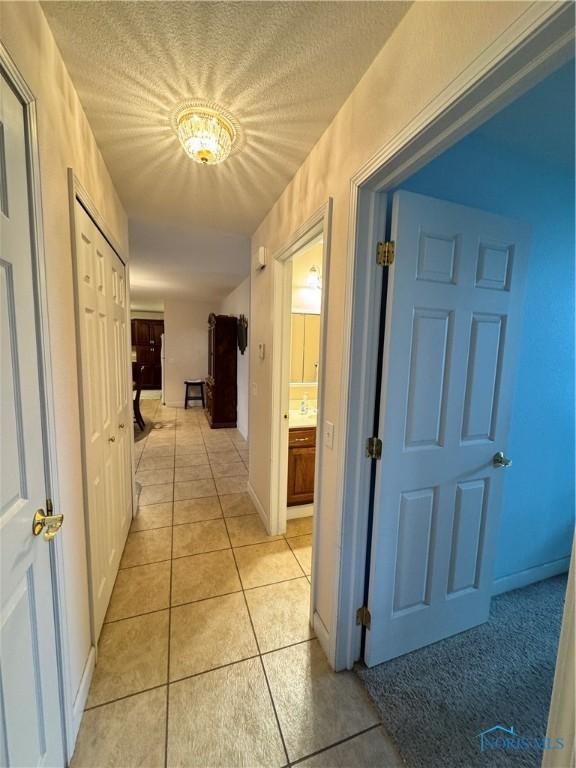 corridor featuring light tile patterned floors and a textured ceiling