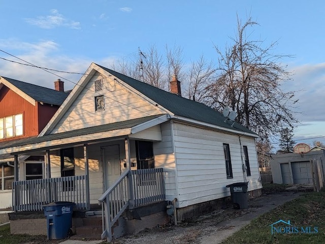 view of front of property with a garage, covered porch, and an outdoor structure