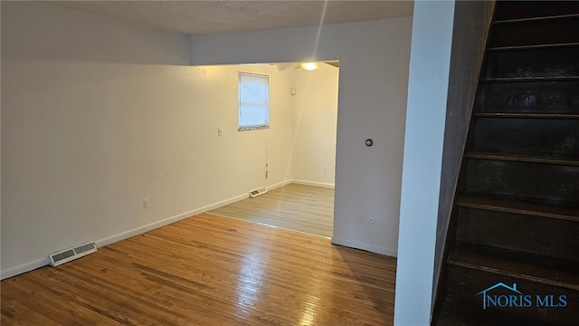 empty room with a textured ceiling and hardwood / wood-style flooring