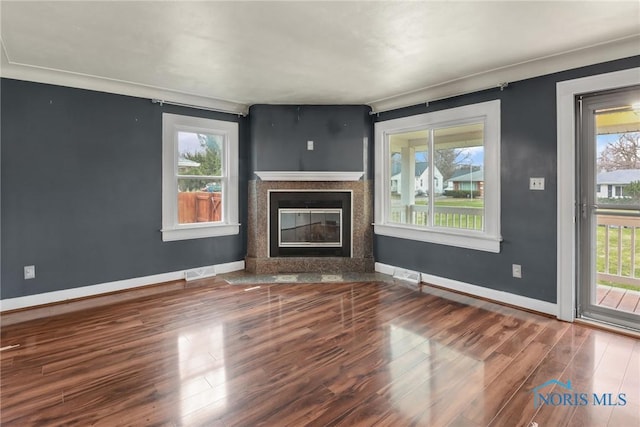 unfurnished living room featuring a fireplace, a healthy amount of sunlight, and hardwood / wood-style flooring