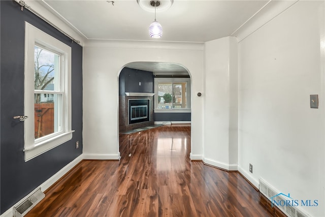 corridor with a wealth of natural light, dark hardwood / wood-style floors, and ornamental molding