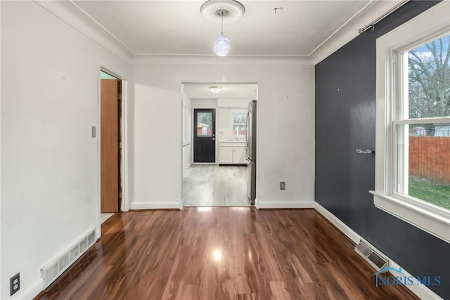 spare room with dark hardwood / wood-style floors, a wealth of natural light, and crown molding