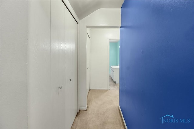 hallway featuring light colored carpet and vaulted ceiling