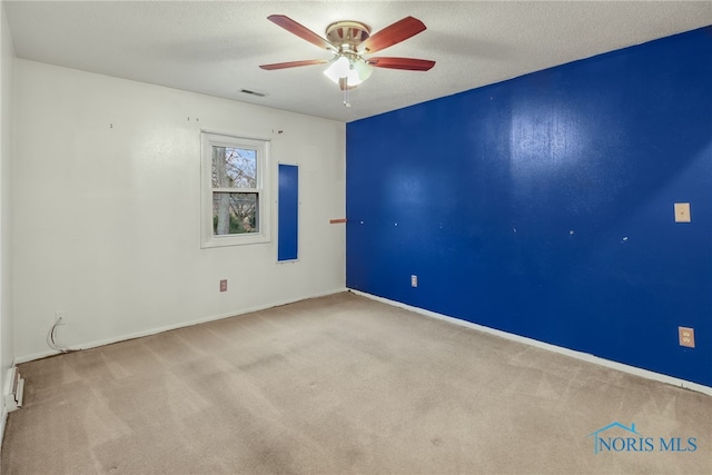 unfurnished room with ceiling fan, a textured ceiling, and light carpet