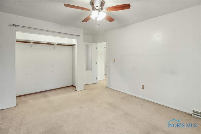 unfurnished bedroom featuring ceiling fan, a closet, light carpet, and a textured ceiling