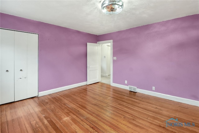 unfurnished bedroom with wood-type flooring and a closet