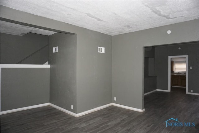 empty room with dark hardwood / wood-style flooring and a textured ceiling