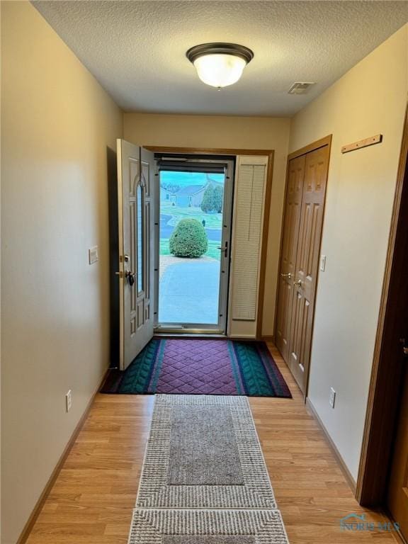 doorway featuring a textured ceiling and light hardwood / wood-style flooring