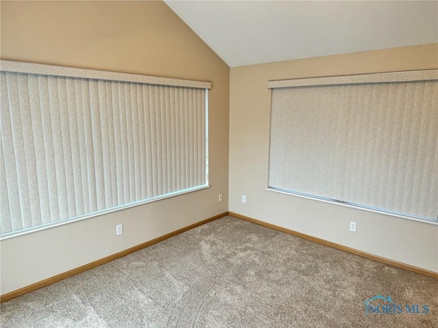 carpeted spare room featuring lofted ceiling