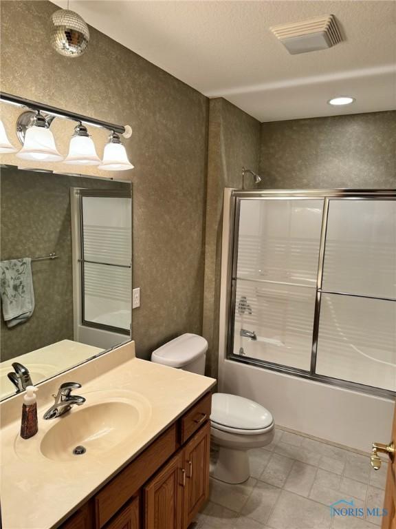 full bathroom with shower / bath combination with glass door, vanity, and toilet