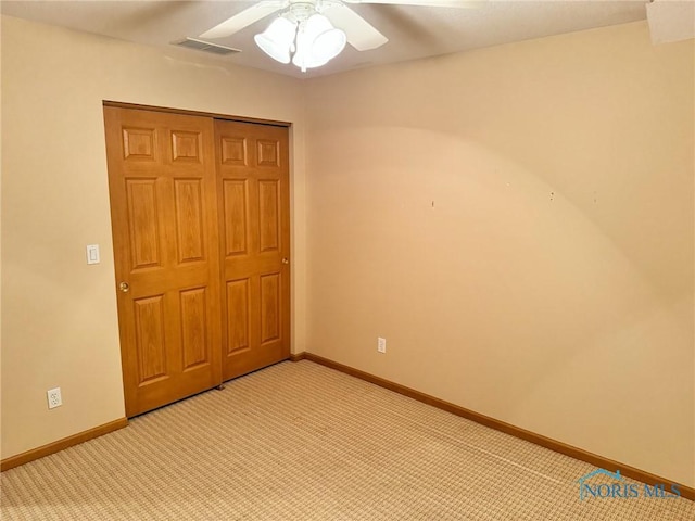 unfurnished bedroom with ceiling fan, a closet, and light colored carpet