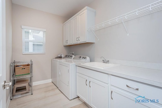 washroom with cabinets, light wood-type flooring, washer and dryer, and sink