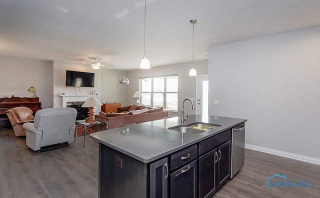 kitchen with stainless steel dishwasher, ceiling fan, sink, hanging light fixtures, and an island with sink