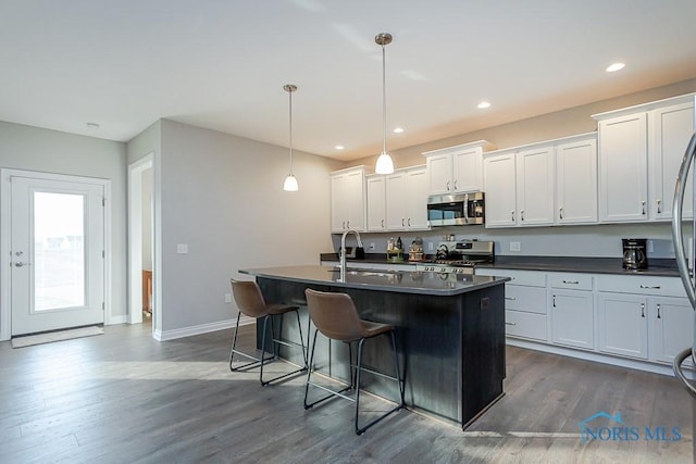 kitchen with a kitchen island with sink, pendant lighting, stainless steel appliances, and sink