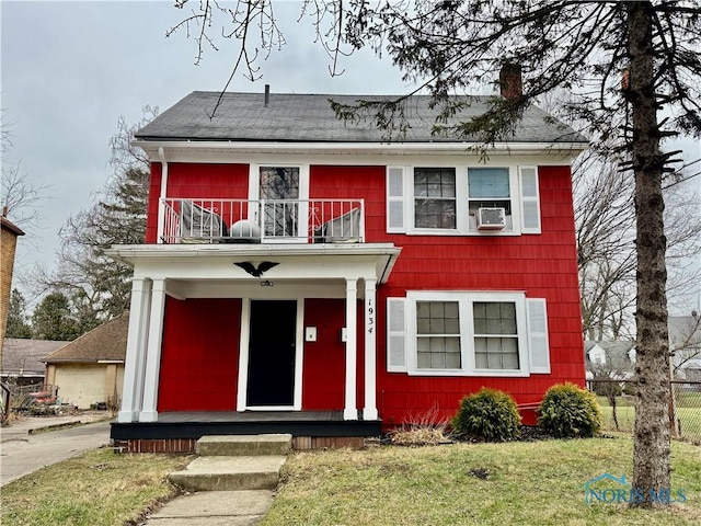 view of front of home featuring a porch, a balcony, cooling unit, and a front yard