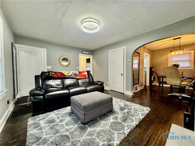 living room featuring dark hardwood / wood-style floors, a textured ceiling, and a chandelier