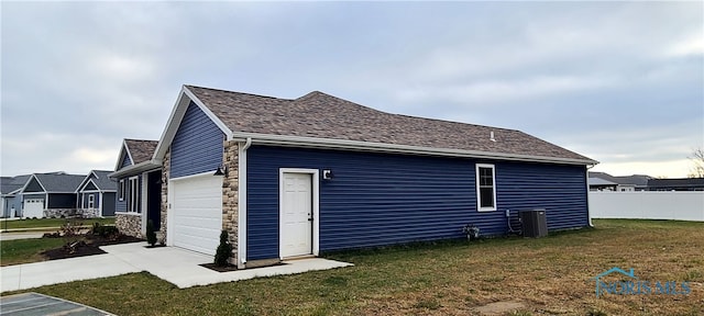 view of side of home featuring a garage, cooling unit, and a lawn